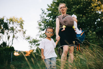 Portrait of mother with children standing on field against trees