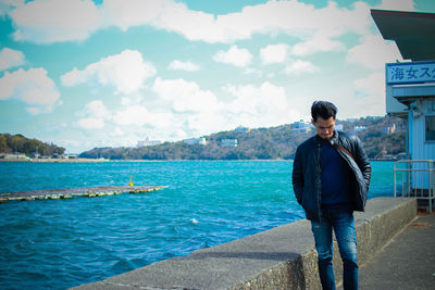 Young man looking at sea against sky