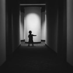 Rear view of silhouette man standing in corridor of building