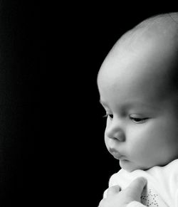 Close-up portrait of cute baby girl over black background