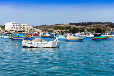 Boats moored on sea against clear blue sky