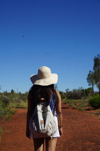 Rear view of woman standing against clear blue sky