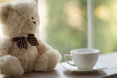 Close-up of teddy bear and coffee cup on table