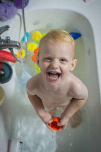 Smiling toddler looking up at the camera in the bathtub