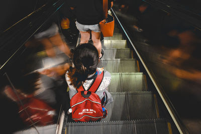 Rear view of woman walking on escalator