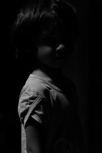 Portrait of boy standing against black background