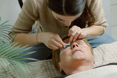 A girl cosmetologist laminates women's eyelashes.