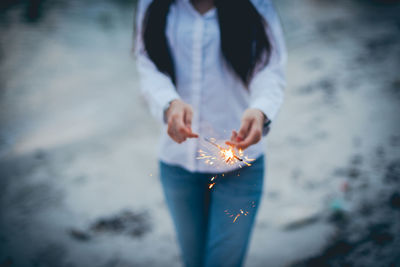 Midsection of woman holding sparkler