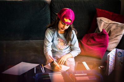 Girl drawing on book on table at home