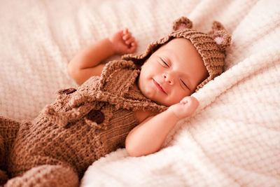 Smiling newborn baby sleeping on bed at home