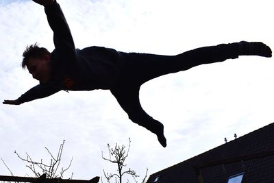 Low angle view of man climbing up against sky