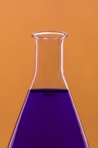 Close-up of purple liquid in flask against orange background