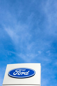 Low angle view of road sign against blue sky