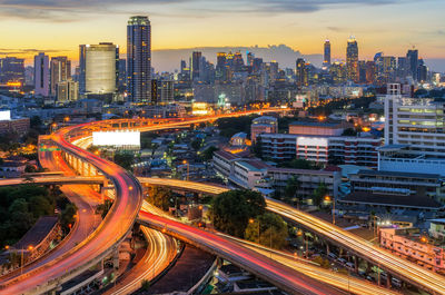 High angle view of light trails on street amidst buildings in city at night