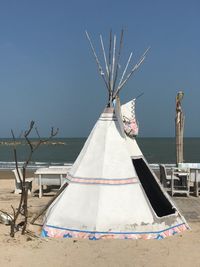 Traditional windmill on beach against clear blue sky