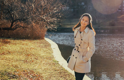 Portrait of smiling young woman standing by tree