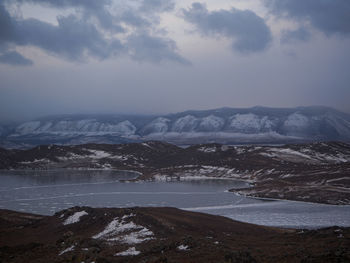 Scenic view of sea and snowcapped mountains against sky