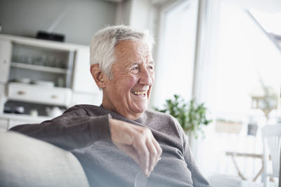 Portrait of laughing senior man sitting on couch at home