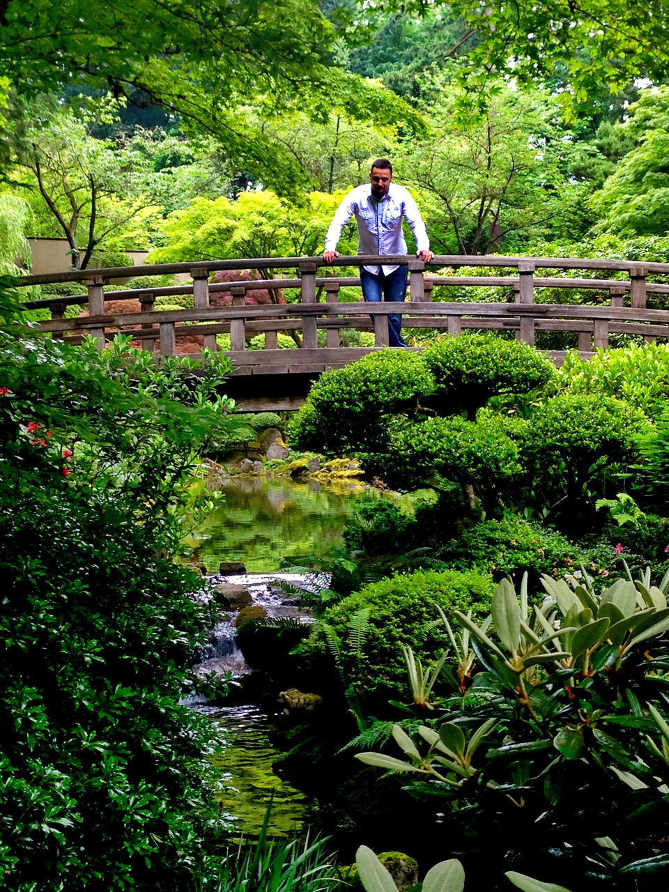 MAN STANDING ON FOOTBRIDGE OVER WATER