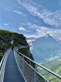 Footbridge over mountain against sky