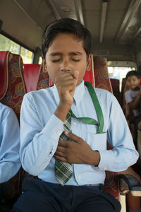 Close-up of boy coughing in school bus