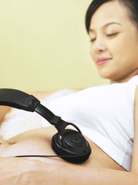 Pregnant woman wearing headphones on belly at home