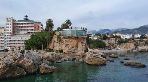 Sea by buildings against sky