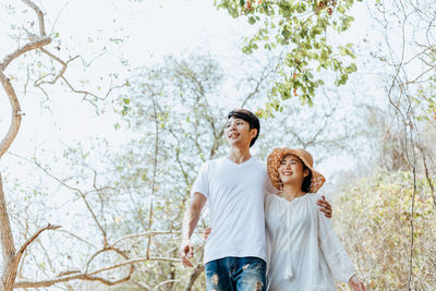 Young couple standing against plants