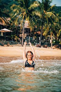 Smiling woman splashing water in sea