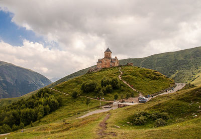 Scenic view of building and mountains against cloudy sky