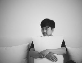 Man holding cushion while sitting on sofa at home