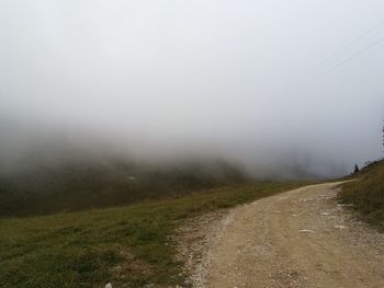 Dirt road along landscape against sky