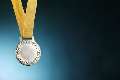 Close-up of silver medal against blue background