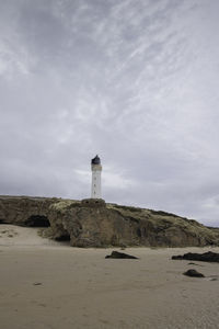 Lighthouse by sea against sky