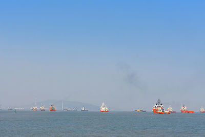 Sailboats sailing in sea against clear sky