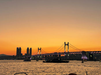 Suspension bridge over river at sunset