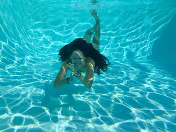 Young woman smiling looking in camera underwater in turquoise transparent water
