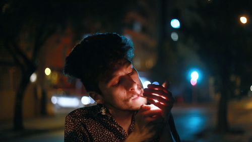 Side view of young woman drinking water at night