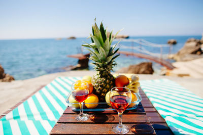 Close-up of drink and fruits on table against sea
