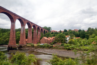 Arch bridge over river against sky