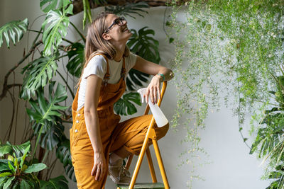 Smiling florist standing on step ladder at flower shop