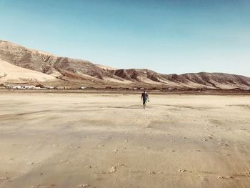 Full length of man on arid landscape against clear sky