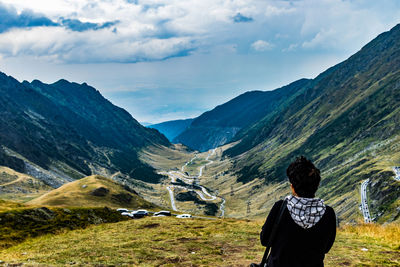 Rear view of man looking at mountains against sky