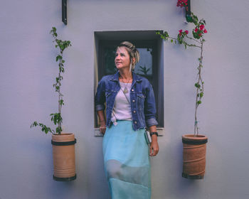 Woman standing by potted plant against building