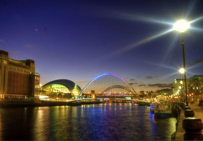 Illuminated bridge over river at night