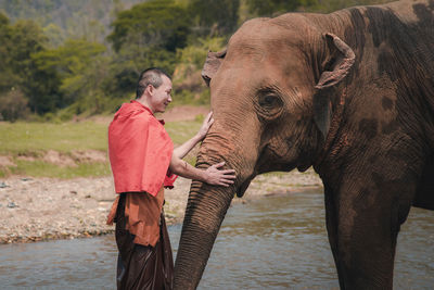 Full length of man standing by elephant in water