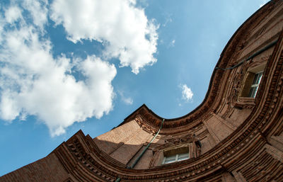 Directly below shot of building and cloudy sky on sunny day