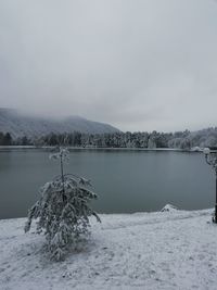 Scenic view of frozen lake by snowcapped mountain against sky