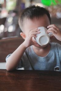 Boy drinking coffee at table in cafe