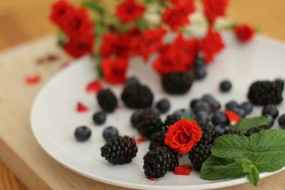 Close-up of blackberries and rose in plate on table